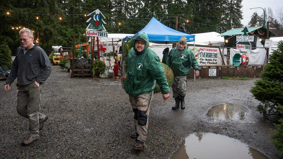 Jordan Boyd (center) and Rick Patterson help Howard Nelson of Gig Harbor with his Christmas tree at Patterson’s Farm Market in Gig Harbor, Washington, on Tuesday, Dec. 20, 2022.