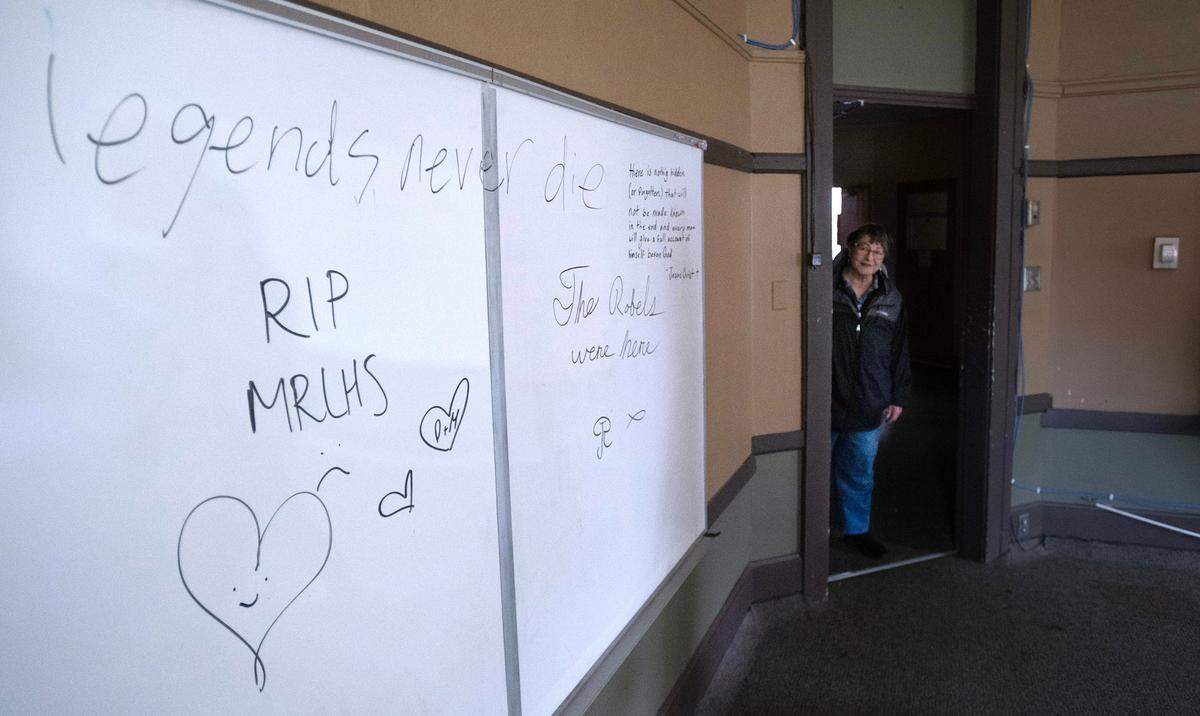 Wendy Freeman, co-secretary of the Parkland Community Association, peeks in at farewell message from 2018 that remain on the whiteboard in a classroom the former Parkland School building in Parkland, Washington, on Tuesday, June 4, 2024. The association purchased the building with plan of turning it into a community center and multi-agency hub.