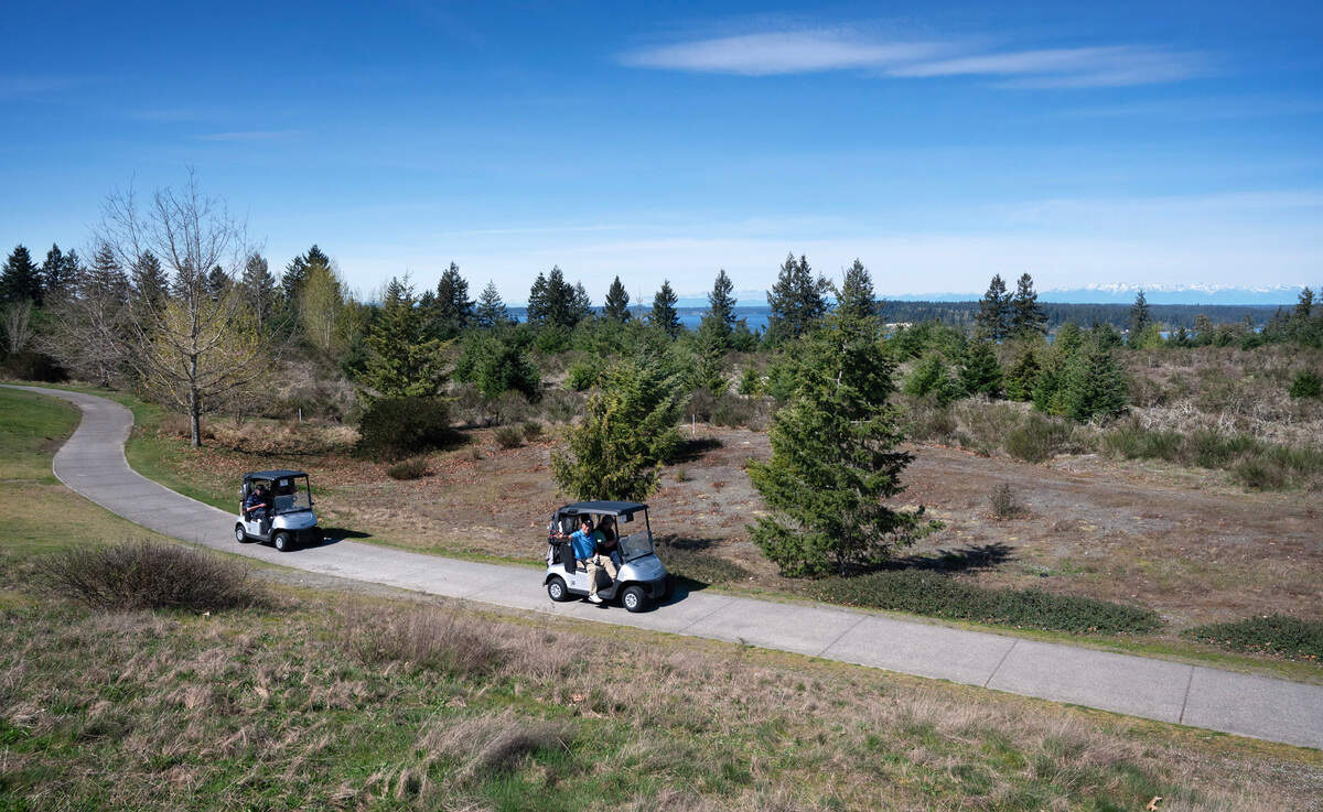 Golfers on The Home Course golf course roll past the undeveloped land planned for housing, commercial property and open spaces in Dupont, Washington, on Tuesday, April 3, 2024. 