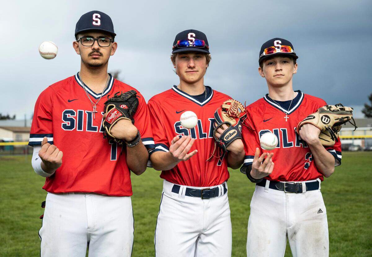 Silas High School varsity baseball players Joseph Gutierrez, left, Gavin Yoder, center, and Nathan Eisenmenger, right, pose for a portrait on the field at Silas High School on Thursday, April 21, 2022 in Tacoma, Wash.