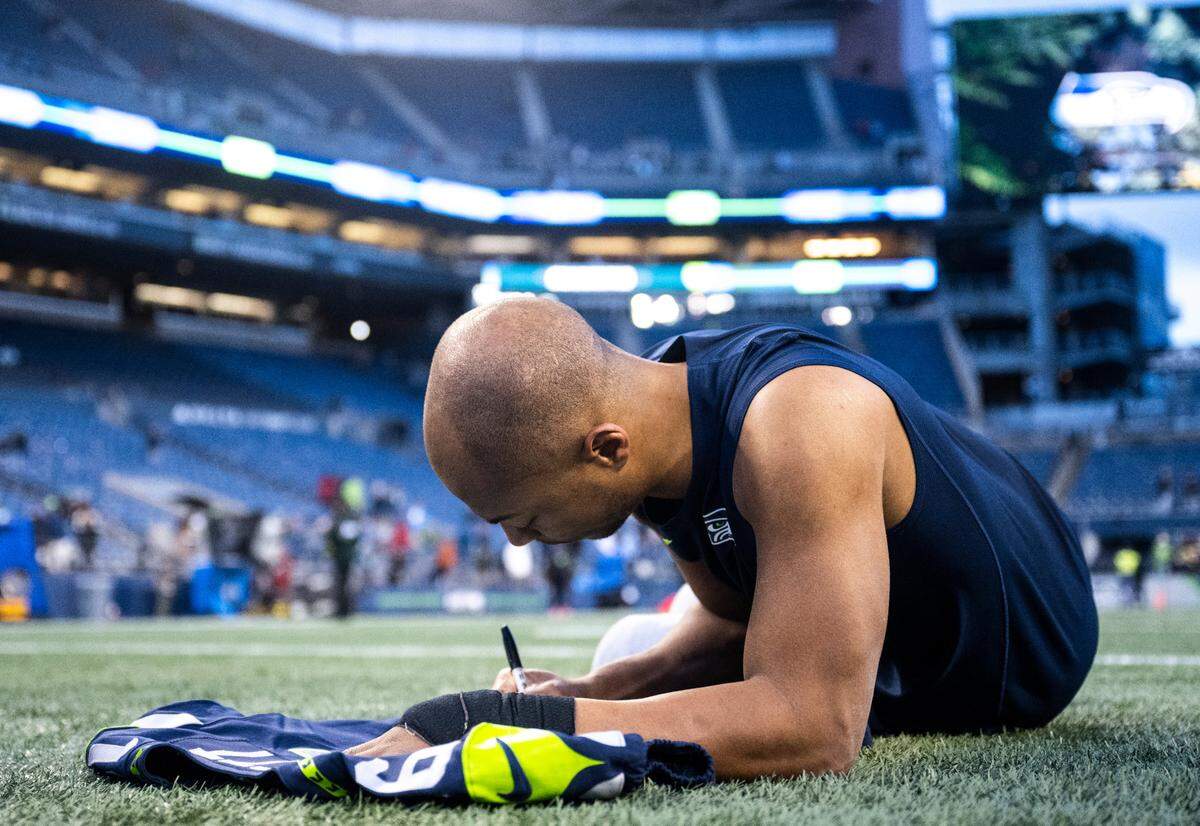Seattle Seahawks wide receiver Tyler Lockett (16) signs a jersey on the field after an NFL game against the New York Jets at Lumen Field in Seattle Wash. on Jan. 1, 2023. The Seahawks defeated the Jets 23-6.