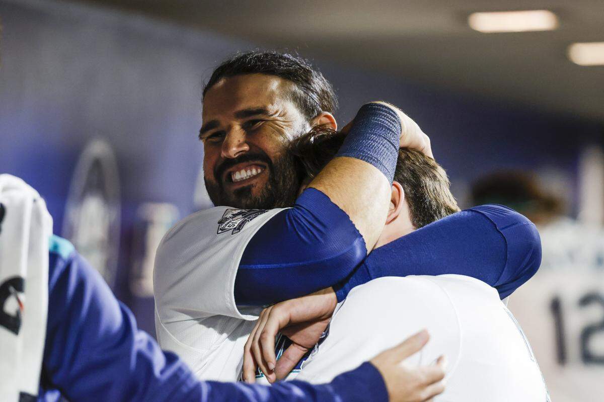 Aug 9, 2025; Seattle, Washington, USA; Seattle Mariners third baseman Eugenio Suárez (28) hugs second baseman Cole Young (2) following a run by Young against the Tampa Bay Rays during the sixth inning at T-Mobile Park. Mandatory Credit: Joe Nicholson-Imagn Images
