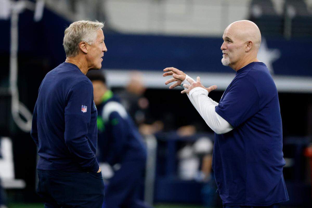 Seattle Seahawks head coach Pete Carroll, left, and Dallas Cowboys Defensive Coordinator Dan Quinn, right, talk on the field during warmups before a preseason NFL football game in Arlington, Texas, Friday, Aug. 26, 2022. (AP Photo/Michael Ainsworth)