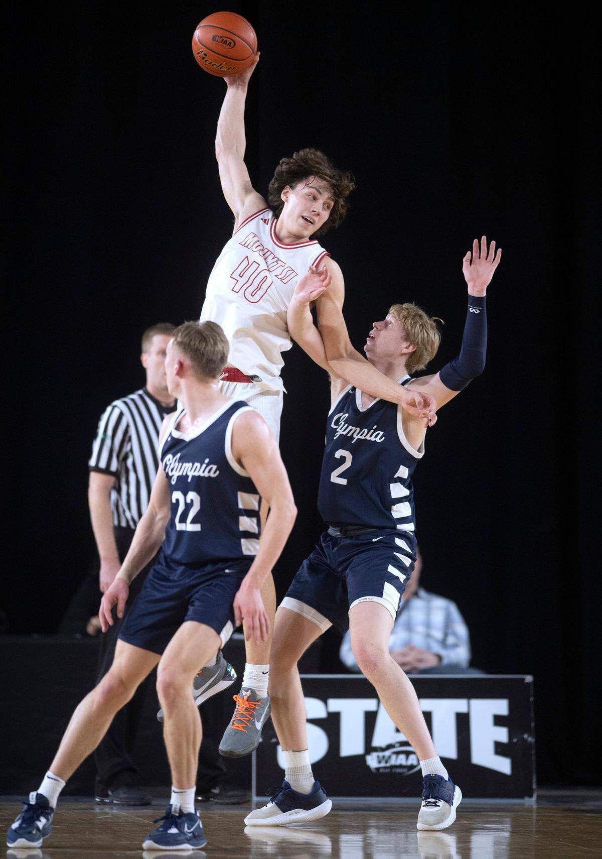 Mount Si’s Miles Heide pulls down a pass over Olympia defenders Parker Gerrits (22) and Andreas Engholm during their state semifinal game at the WIAA state basketball tournament in the Tacoma Dome in Tacoma, Washington, on Friday, March 3, 2023.