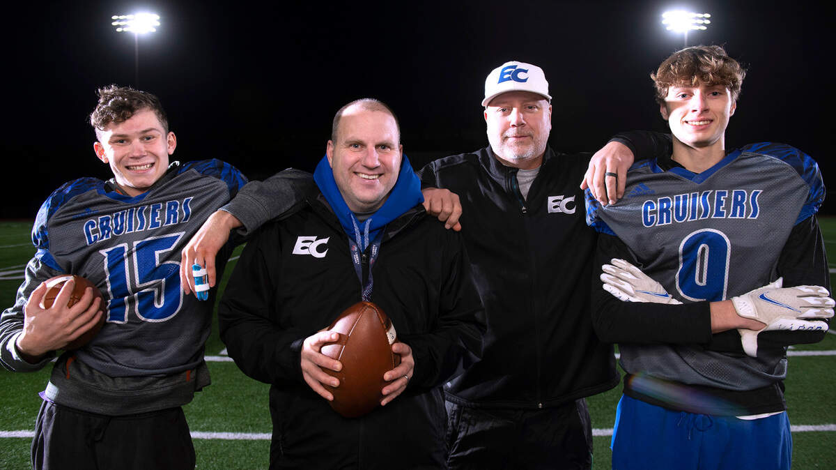 Eatonville football head coach Gavin Kralik (center left) and assistant coach Bobby Lucht - who quarterbacked the Cruisers to their last state championship in 1992 - are getting to coach their sons, junior receiver Job Kralik (far left) and senior receiver Jackob Lucht, into the state semifinals on Saturday. They are show before football practice at Art Crate Field in Spanaway, Washington, on Tuesday, Nov. 23, 2021.
