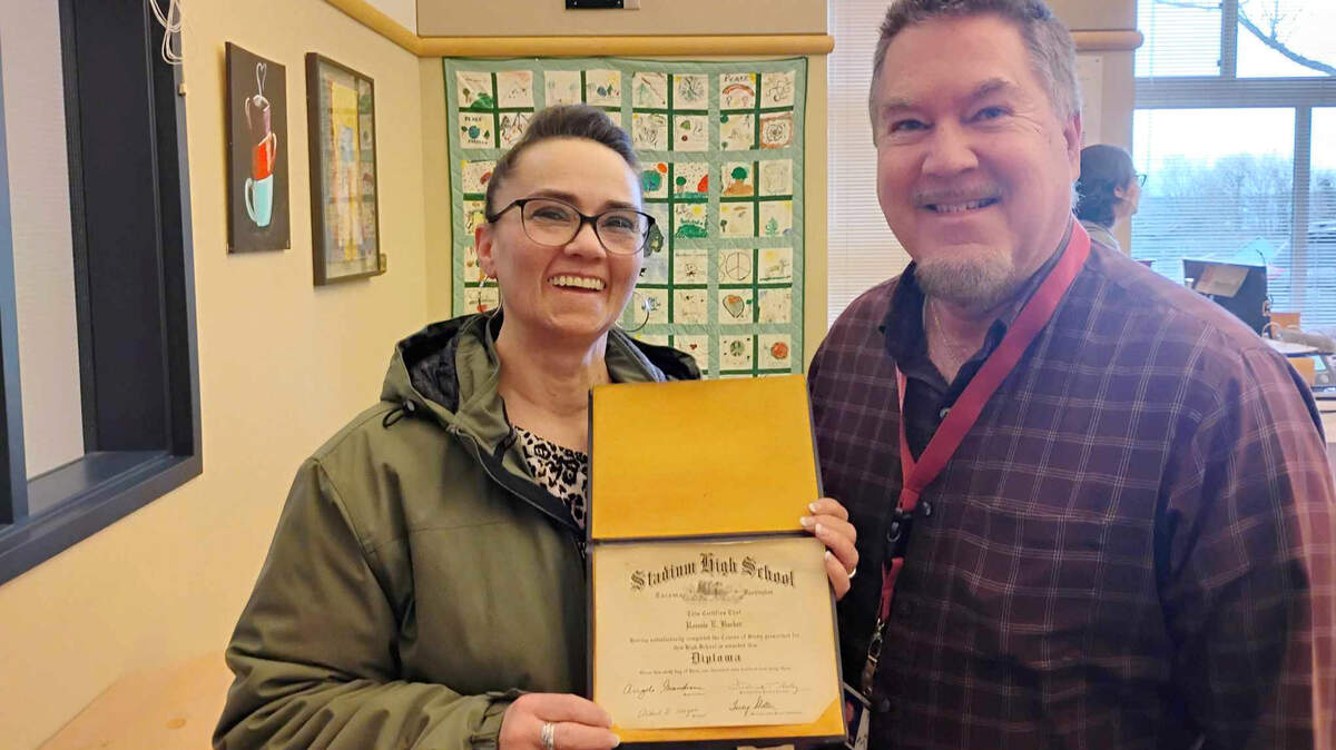 Jennifer Moberg holds the high school diploma that belonged to her fiance’s father, Ronnie E. Barker. Johnny Joyce, right, found the diploma at Blix Elementary School on March 19, 2025.