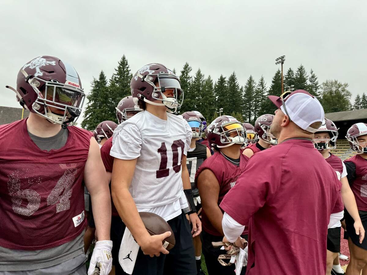 Enumclaw High School football players gather around coach Mark Gunderson on the first day of practice on Wednesday, Aug. 20, 2025 at Enumclaw Stadium.