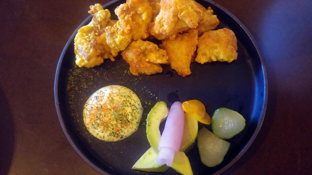 An order of chicken karaage with cured egg yolk dipping sauce and pickled vegetables from Moshi Moshi Bar + Ramen.
