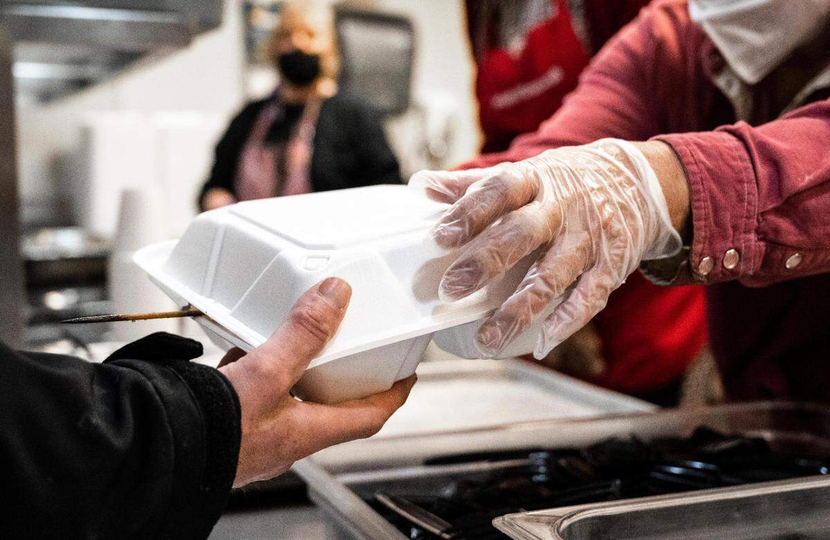 Volunteers serve warm meals to unhoused community members at the Tacoma Rescue Mission on Thursday, April 14, 2022 in Tacoma, Wash. The downtown homeless shelter will be closing its kitchen for approximately two months to do renovations that will expand their facilities and allow them to serve the community more.