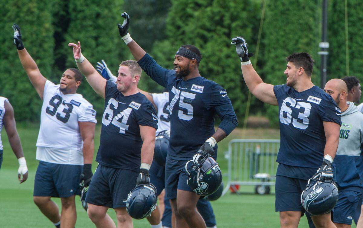 Veteran defensive tackle -- and rancher -- Al Woods (93) joins Seahawks teammates in waving to fans at the end of the fourth day of Seahawks training camp Saturday, July 31, 2021 at the Virginia Mason Athletic Center in Renton. From left: Woods, defensive tackle Walt Palmore, offensive tackle Greg Eiland and offensive lineman Jared Hocker.