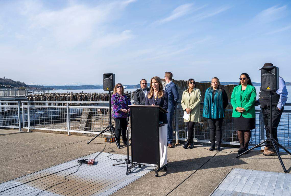 Commissioner of Public Lands Hilary Franz stands at a podium on the former Dickman Mill site where 1,200 polluted creosote pilings have remained in the water for decades and may possibly be removed if legislation is passed, during a press conference to announce her support for two companion bills making their way through the state legislature on March 17, 2023 in Tacoma, Wash.