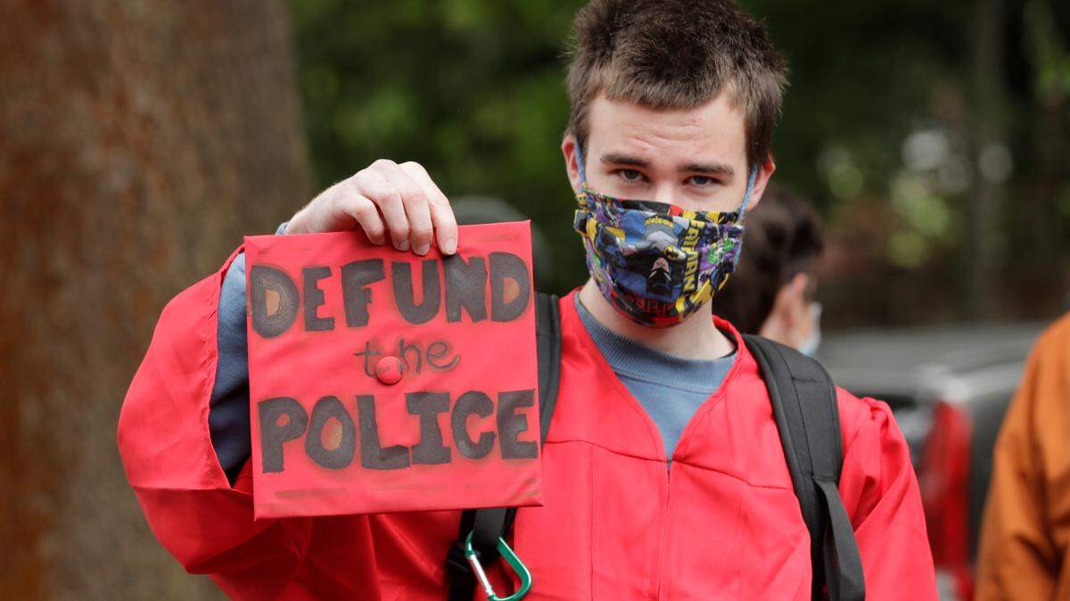 Elliot Armitage, a 2020 graduate of Ballard High School, holds his mortarboard cap that reads “Defund the Police” as he prepares to take part in a cap and gown Black Lives Matter march with other high school graduates, Monday, June 15, 2020, in Seattle. The theme of the march as “Walking for Those Who Can’t,” and organizers were calling for police funding reforms and an end to Seattle public schools’ relationship with the Seattle Police Department.