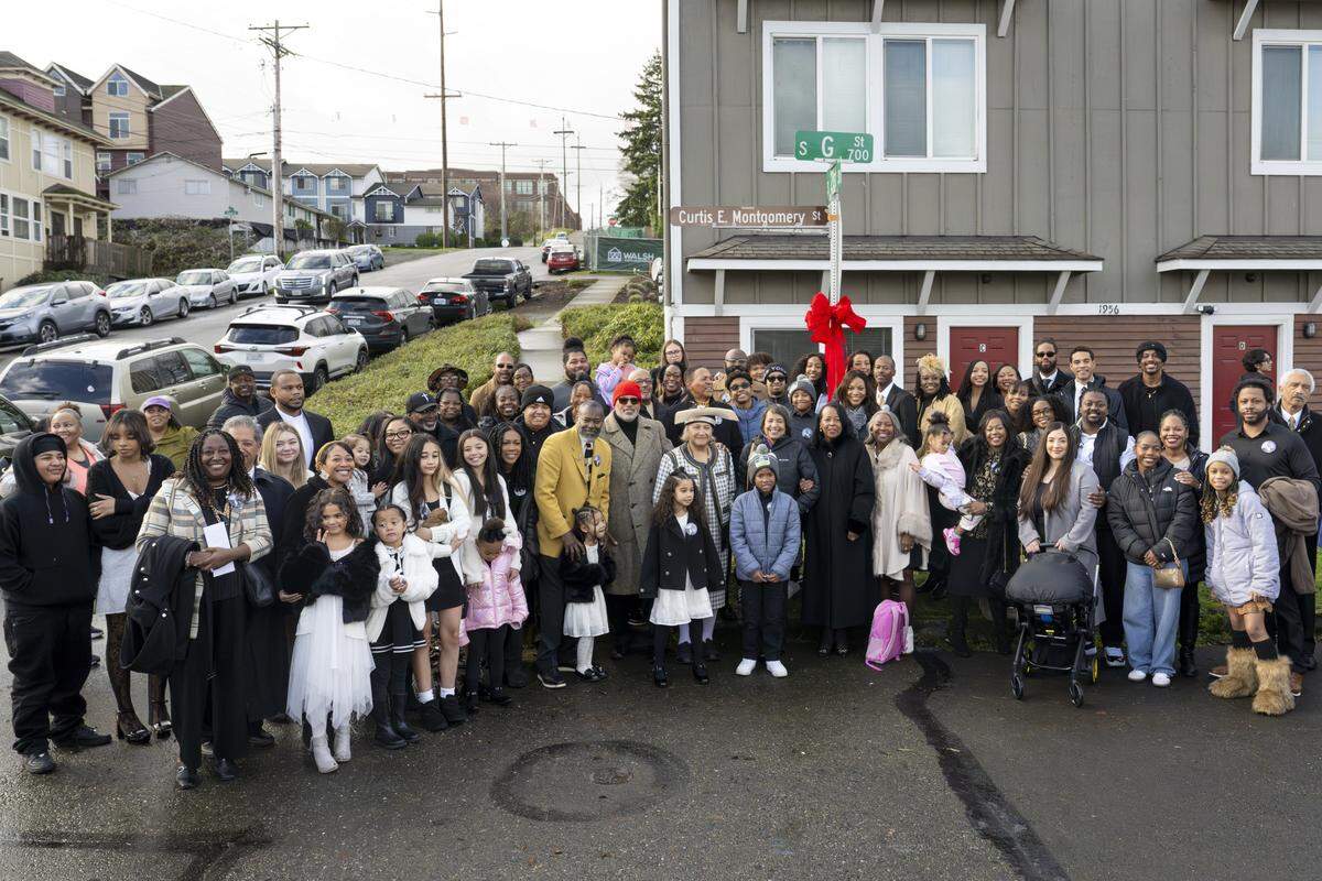 Family of Bishop Curtis E. Montgomery, along with Mayor Victoria Woodards, gather for a photo in front of the honorary Curtis E. Montgomery Street sign on Saturday, Dec. 27, 2025, at the intersection of G and South 21st streets in Tacoma, Wash.