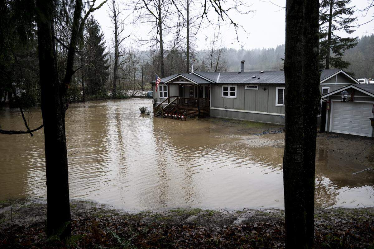 A home is surrounded by water as an evacuation warning is in place for homes near the South Prairie Creek, on Thursday, Dec. 11, 2025, in South Prairie, Wash.