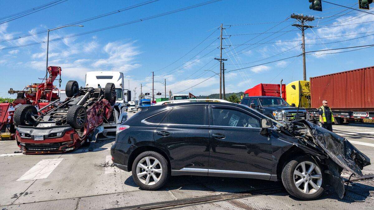 Tacoma Police officers direct traffic as cleanup begins after a three-vehicle collision at the intersection of Taylor Way East and state Route 509 on Thursday, July 21, 2022, in Tacoma, Wash. As a result of the crash, a truck rolled onto the front end of the semi truck. No one was injured in the collision, however traffic was backed up in all directions as the road was cleared of the vehicles and debris left over from the wreck.