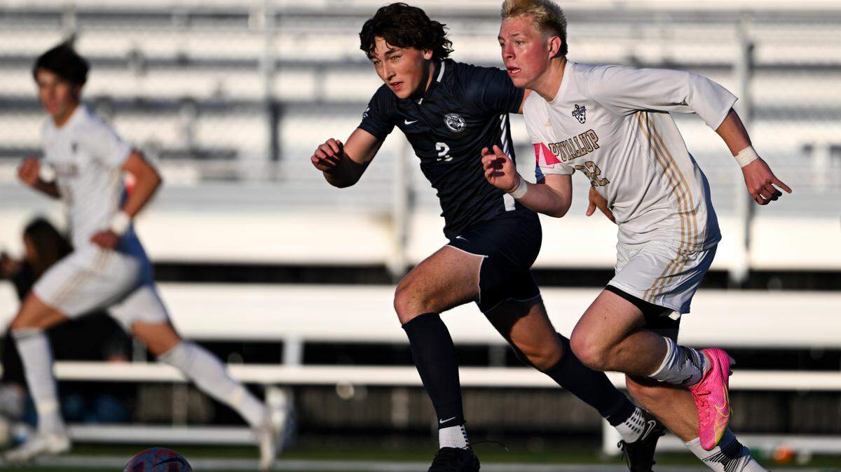 Bellarmine Prep defender Rory O’Reilly and Puyallup midfielder Zack Robertson (22) chase down the ball during the match at Bellarmine Preparatory School, on Tuesday, April 16, 2024, in Tacoma, Wash.