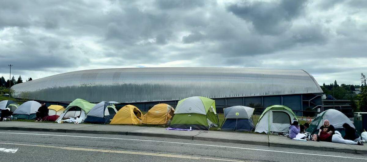 With LeMay - America’s Car Museum in the background, campers line up Monday for Tuesday’s Tomorrow X Together show at the Tacoma Dome.