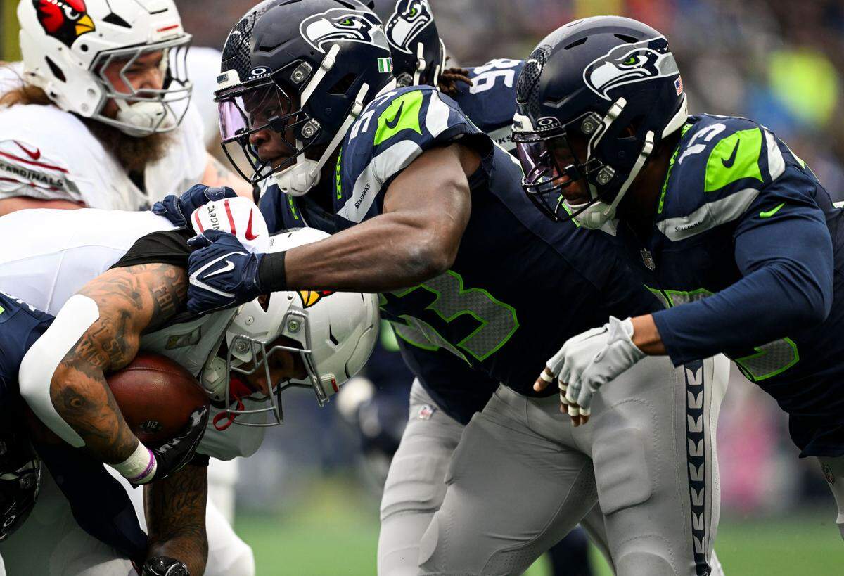 Seattle Seahawks cornerback Devon Witherspoon (21) tackles Arizona Cardinals running back James Conner (6) during the first quarter of the game at Lumen Field, on Sunday, Nov. 24, 2024, in Seattle, Wash.