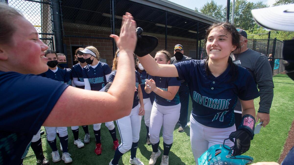 The Ravens’ Melina Ness is congratulated by her teammates after hitting a game-winning double that captured the NPSL softball championship over Tahoma on Saturday, May 22 at Auburn Riverside High School.