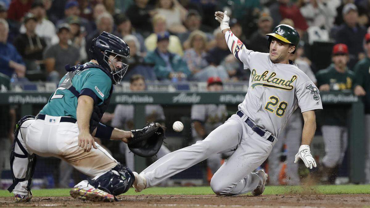 Oakland Athletics’ Matt Olson (28) scores as Seattle Mariners catcher Tom Murphy catches the throw during the seventh inning of a baseball game Friday, July 5, 2019, in Seattle.