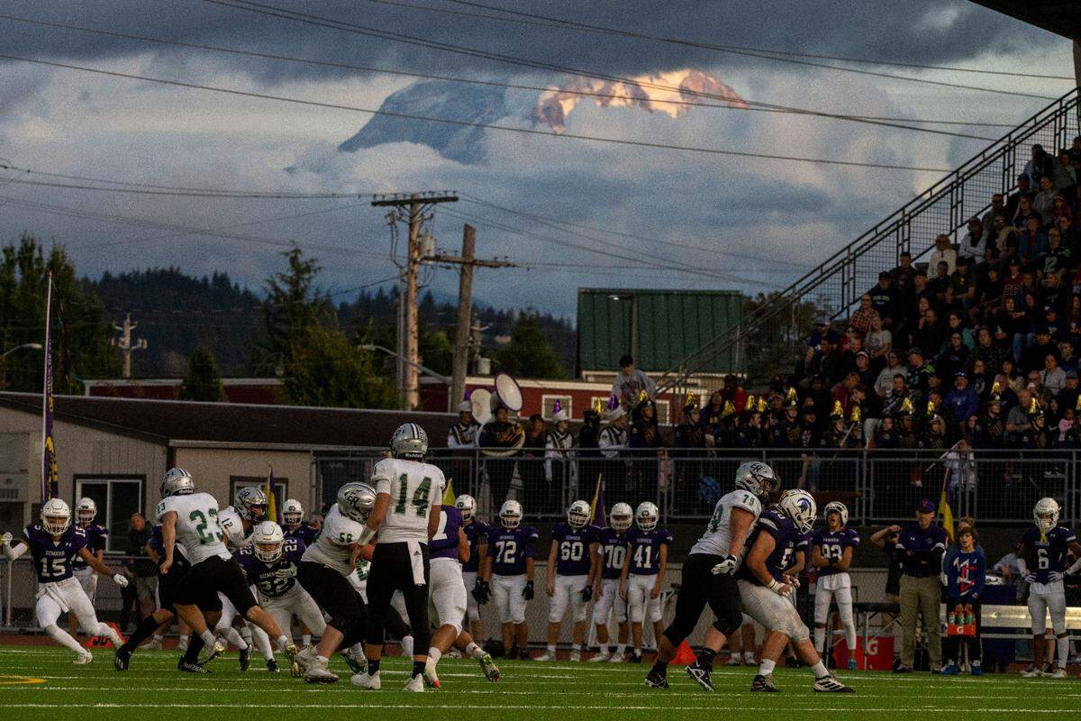 Mount Rainier peaks out through the clouds as Emerald Ridge running back Logan Lisherness carries the ball through the Sumner defense during the first quarter of a 4A SPSL game on Friday, Sept. 16, 2022, at Sunset Chev Stadium in Sumner, Wash.