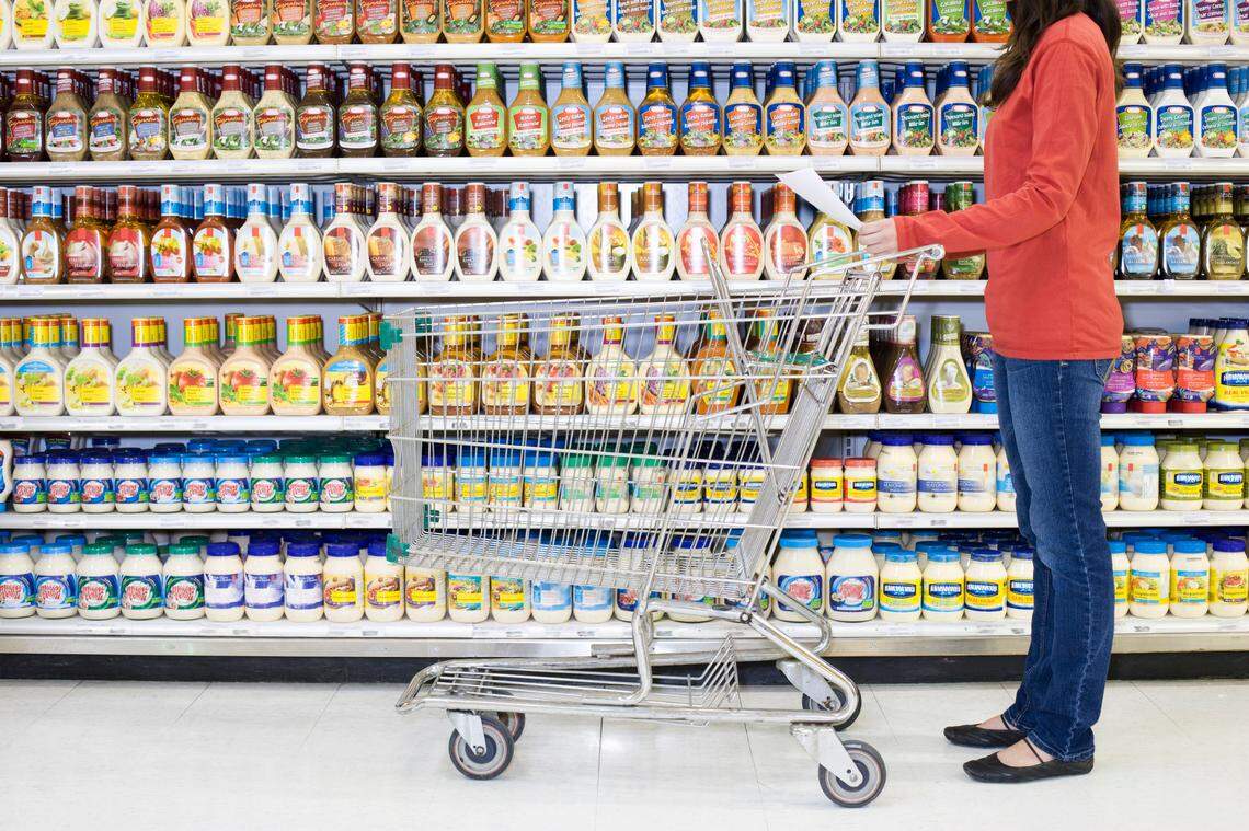 A shopper checks a list in a supermarket aisle.