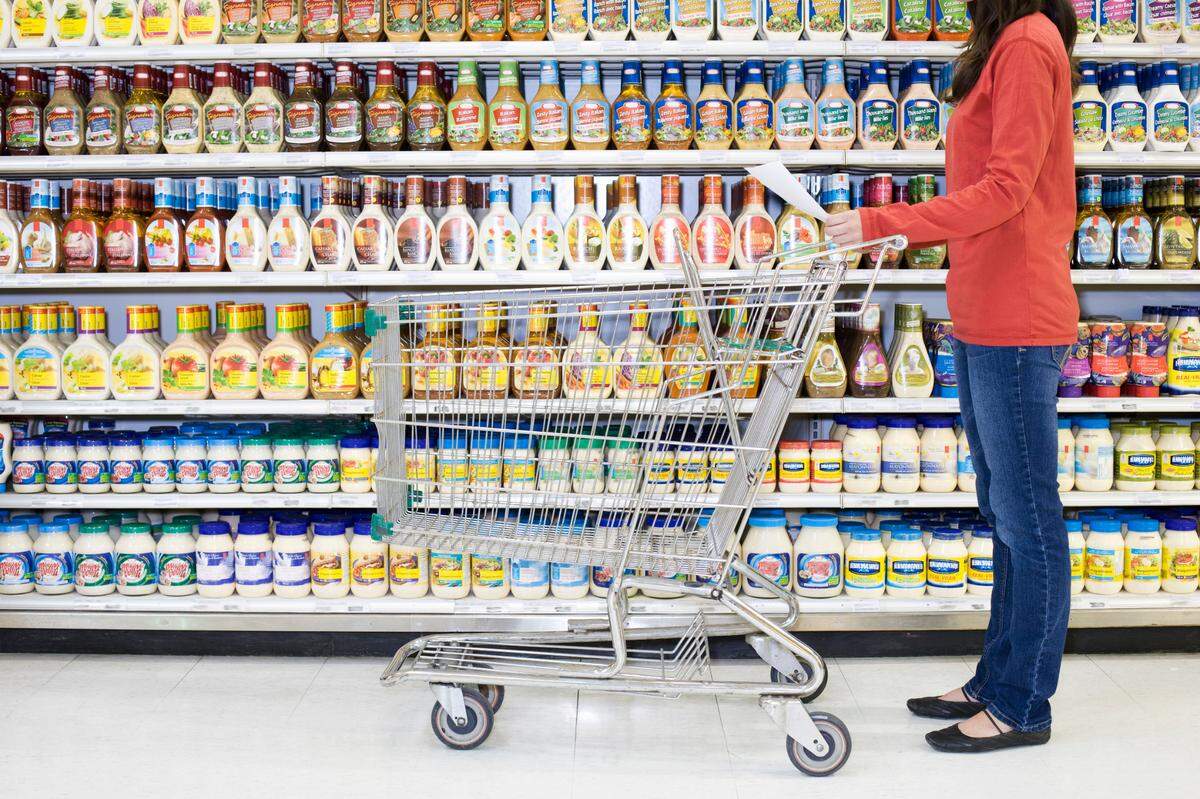 A shopper checks a list in a supermarket aisle.