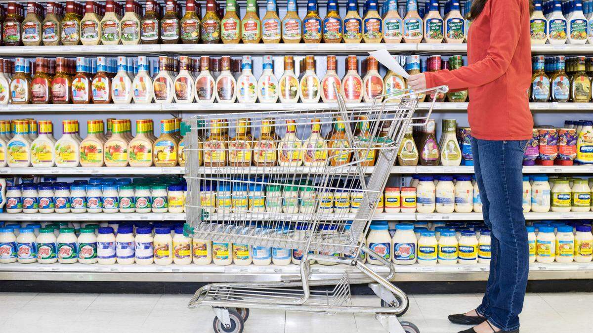 Shopper checking list in supermarket aisle.