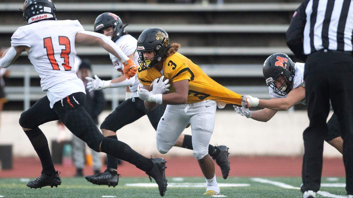 Lincoln running back Navarre Dixon drags a Monroe defender during Saturday afternoon’s 3A state football playoff game at Lincoln Bowl in Tacoma, Washington, Nov. 12, 2022. Lincoln won the game, 49-16.