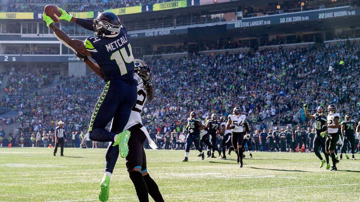 Seattle Seahawks wide receiver DK Metcalf (14) catches pass from quarterback Geno Smith (7) as Jacksonville Jaguars cornerback Shaquill Griffin (26) defends during the second quarter of an NFL game on Sunday at Lumen Field in Seattle. Metcalf would score on the play.