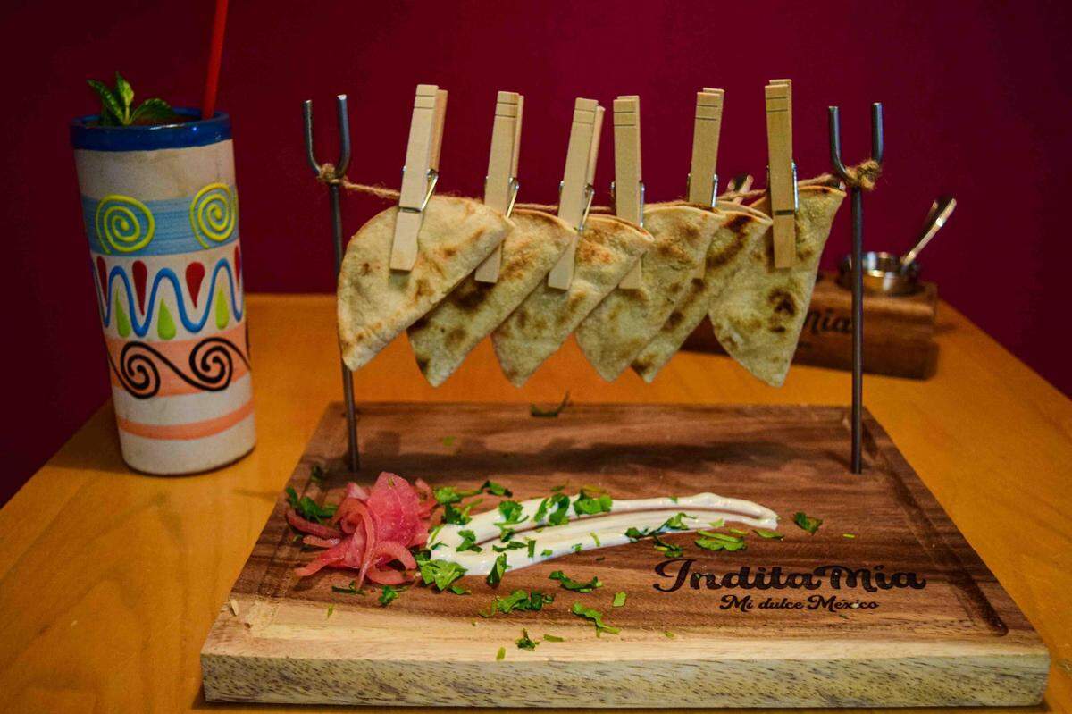 Taquitos, folded with a bit of refried beans, are served playfully with sour cream and pickled onions to garnish.