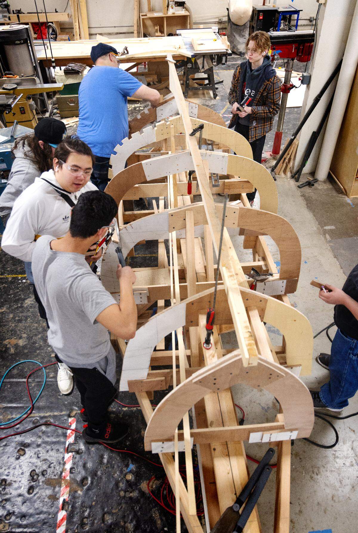 Students at the School of Industrial Design Engineering and Art (IDEA) work along teachers to build a wooden boat as part of the Career and Technical Education (CTE) program.