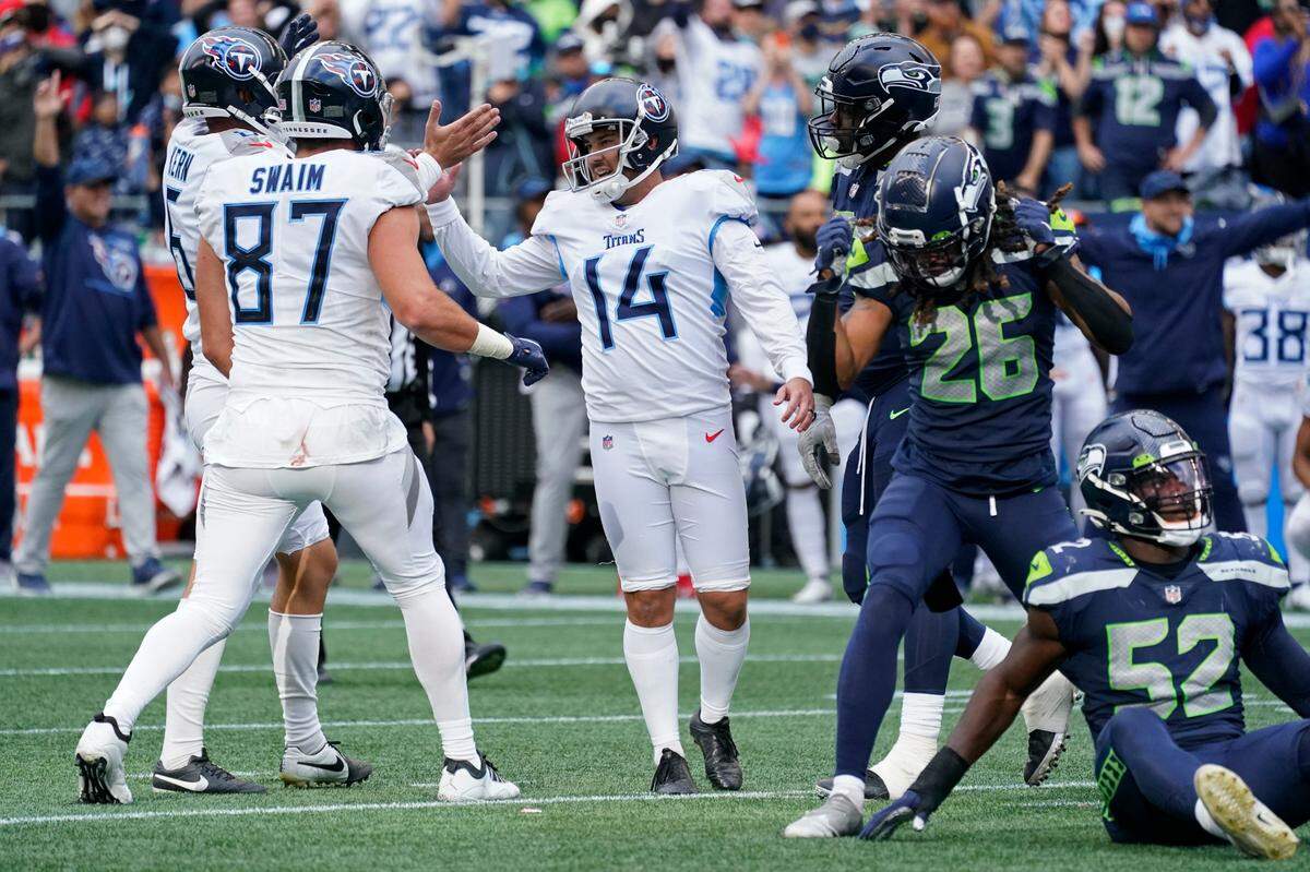 Tennessee Titans kicker Randy Bullock (14) celebrates with tight end Geoff Swaim (87) as Seattle Seahawks defensive back Ryan Neal (26) reacts after Bullock kicked a field goal in overtime to give the Titans a 33-30 win in an NFL football game, Sunday, Sept. 19, 2021, in Seattle. (AP Photo/Elaine Thompson)
