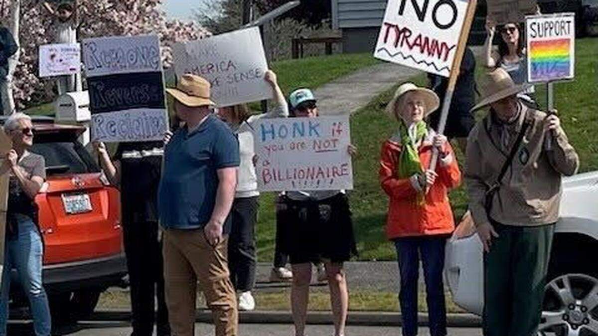 Residents hold signs protesting the Trump administration and special government employee Elon Musk during a protest at Point Defiance in Tacoma on April 5, 2025. A May Day protest is scheduled Thursday in dowtown Tacoma.