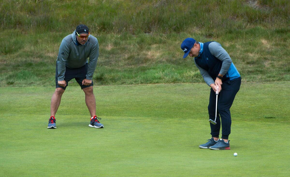 Under the watchful eye of caddie Jack Riggins, Danny Woodhead, a former running back for the New England Patriots, putts during a practice round at Chambers Bay Golf Course in University Place on Friday, May 21, 2021. Woodhead will be competing in the U.S. Amateur Four-Ball Championship.