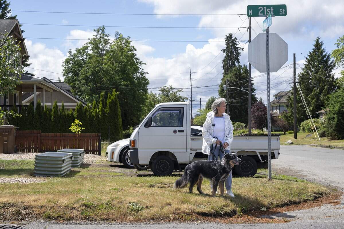 Deb Anderson stands with her dog Roscoe on the corner of North 21st and North Madison streets and watches for traffic on Wednesday, June 10, 2026, in Tacoma, Wash. Anderson lives near North 21st and regularly crosses the intersection to reach the Proctor area.