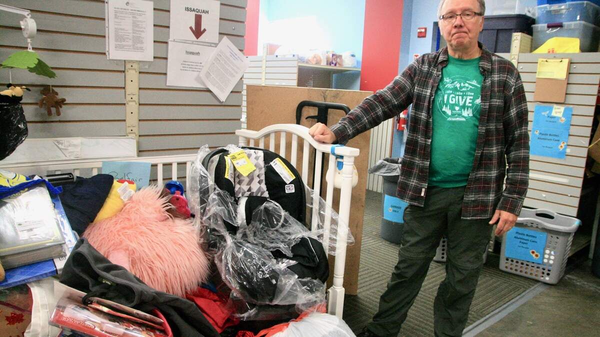 A volunteer prepares to sort clothing items temporarily deposited in a baby crib the Eastside Baby Corner will contribute to someone in need.
