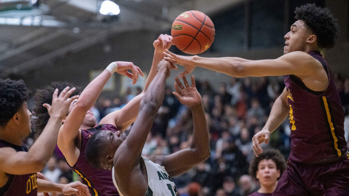 Auburn guard Luvens Valcin (14) is surrounded by O’Dea defenders as he drives into the lane for a shot attempt in the second quarter of a Class 3A state regionals game on Saturday, Feb. 25, 2023, at Auburn High School in Auburn, Wash. Valcin was called for traveling on the play.