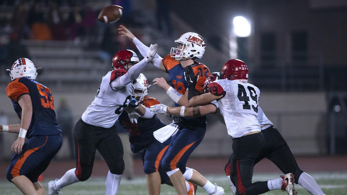 Lakes quarterback Liam Bladow gets rid of the ball under pressure from Yelm defenders Bradley McGannon and David Barlow (49) during Friday night’s 3A football state playoff game at Harry E. Lang Stadium in Lakewood on Nov. 9, 2018.