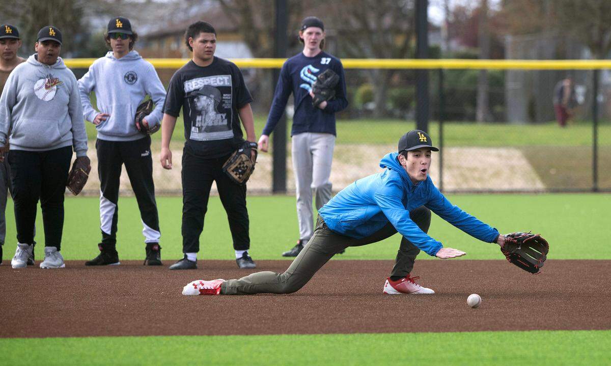 Lincoln baseball player Shinnosuke Nakamura dives for a ground ball as he and his Abe teammates run through practice drills on the new turf field at Lincoln High School in Tacoma, Washington, on Monday, April 8, 2024.