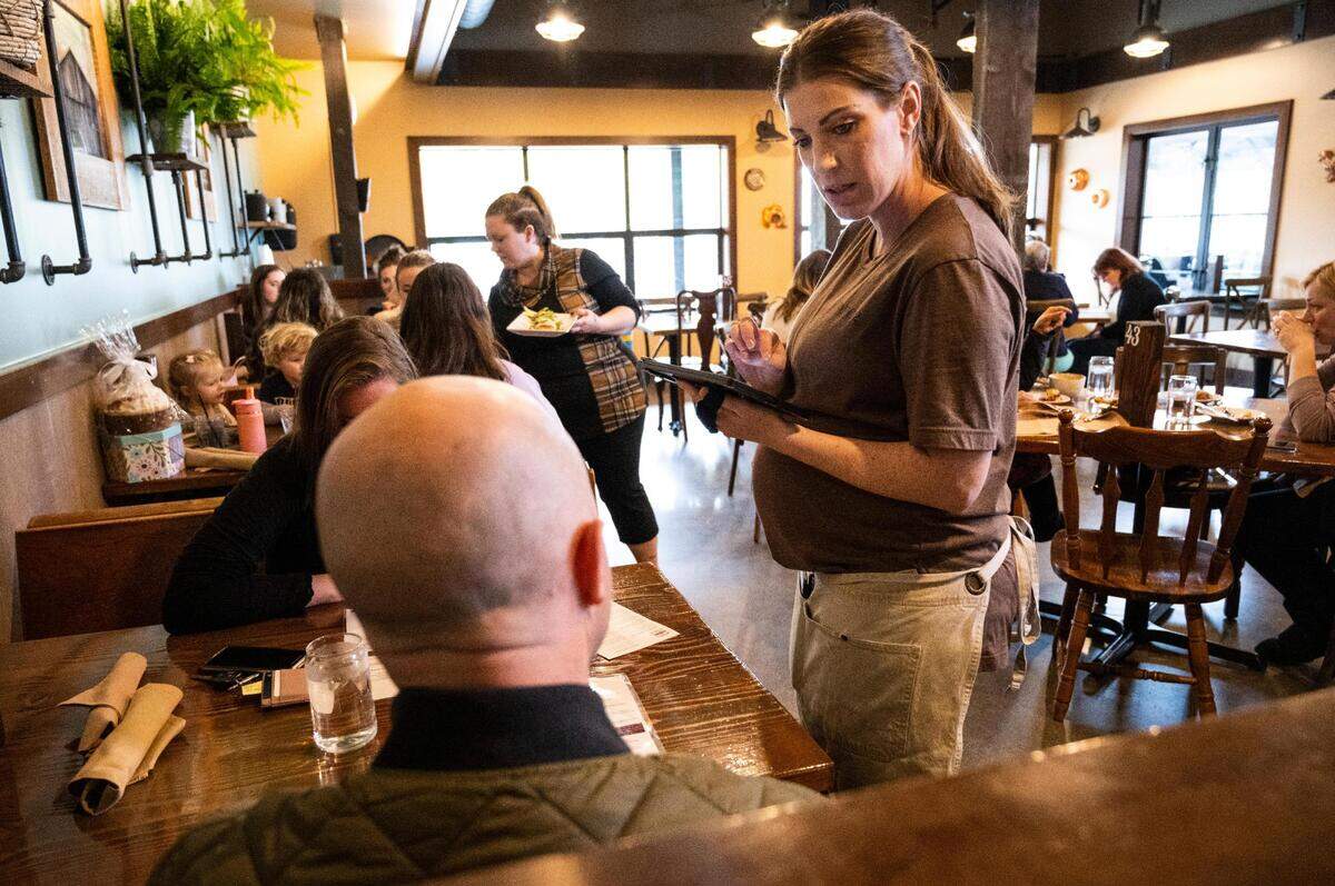 Jowell Scott, a server at Farm12 and single mom of four children with her fifth on the way, waits on a table at Farm12 on Thursday, April 21, 2022 in Puyallup, Wash.