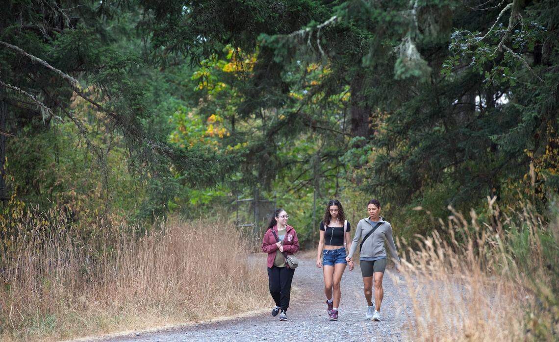 Karen Schlender (right) of Lacey, Washington, and her daughters Eila (left) and Zoey walk out the Sequalitchew Creek Trail in DuPont, Washington, on Thursday, Aug. 15, 2024. Neighbors worry the proposed expansion of Pioneer Aggregates Mine and the subsequent draining of the aquifer will forever destroy the natural beauty Sequalitchew Creek and the surrounding flora and fauna along the popular trail to Puget Sound.
