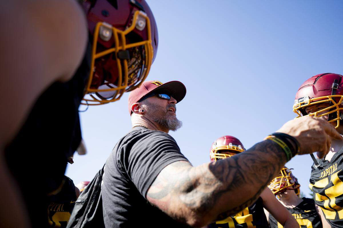 Capital head coach Terry Rose talks to players in the huddle during a football practice at Capital High School on Friday, Aug. 22, 2025, in Olympia, Wash.