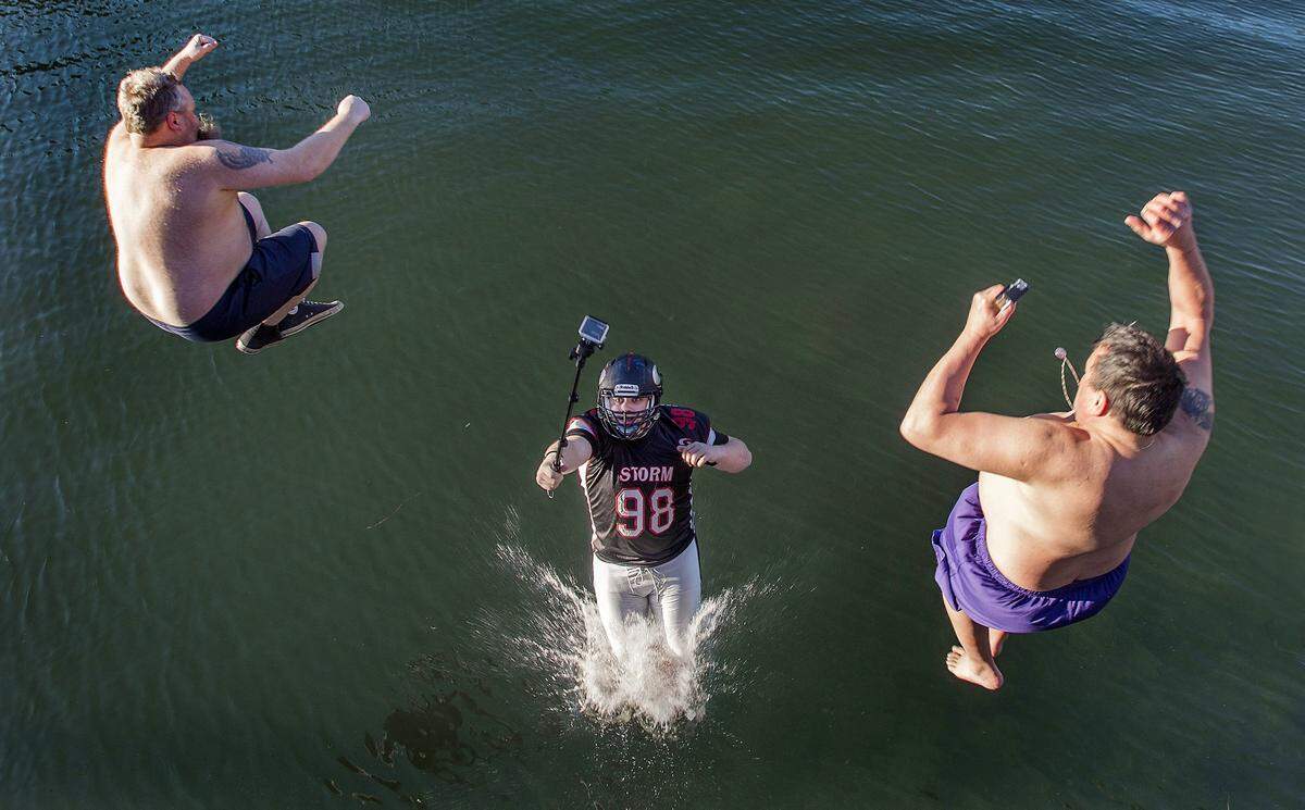 FILE: Proving there’s no venue that can’t be documented with a selfie, Chad Holtquist records his leap off the Olalla Bay bridge wearing his Kitsap Peninsula Storm semi-pro football uniform on Friday, Jan. 1, 2016. He’s flanked by his dad, Chad Sr., left, and Del Lee as they participate in the 32nd annual Polar Bear Plunge.