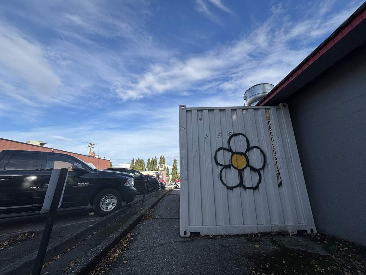 The distinctive daisy associated with Tacoma tagger “XCIT” is seen on a storage container outside a restaurant on Pacific Avenue in downtown Tacoma on Oct. 2, 2025.