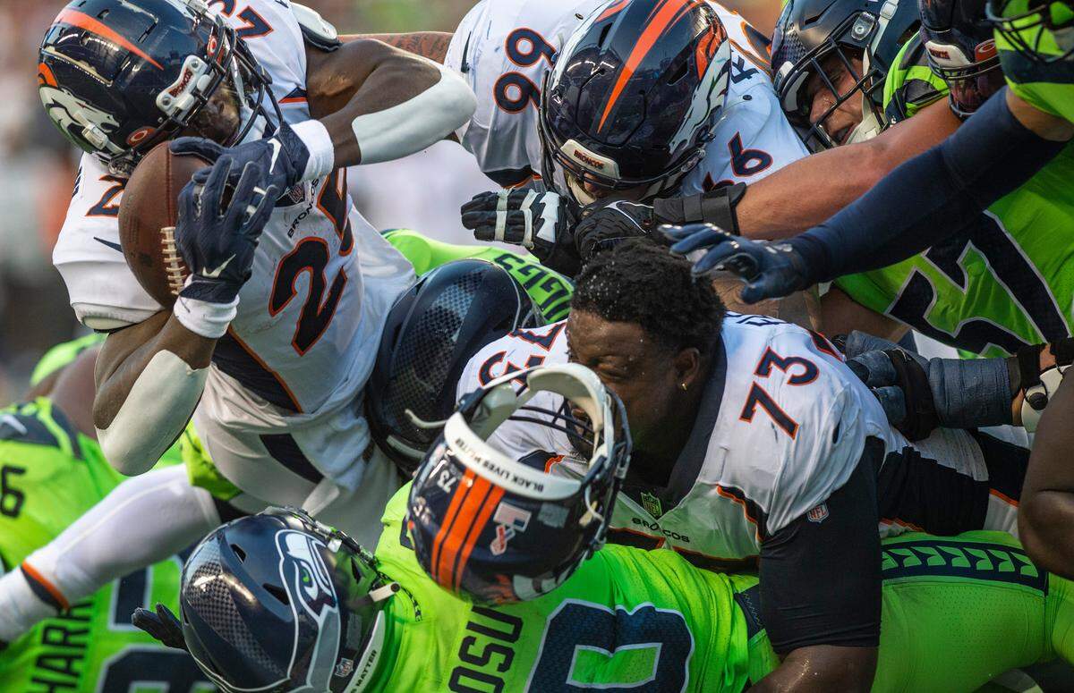 Linebacker Uchenna Nwosu (10, bottom of the pile) and Seahawks teammates stop Denver Broncos running back Melvin Gordon III (25) at the goal line on fourth down in the third quarter of an NFL game on Monday, Sept. 12, 2022, at Lumen Field in Seattle.
