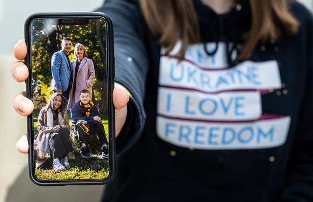 Anastasiya “Ana” Lemesh poses for a portrait with a photograph of her father, Volodymyr Kozel, mother, Nina Lemesh and brother, Artem Lemesh, 14, and herself on her cellphone at Pierce College Fort Steilacoom in Lakewood, Wash. on Thursday, March 31, 2022. Lemesh is from Chernihiv, Ukraine and has been an exchange student in the U.S. for approximately three months.
