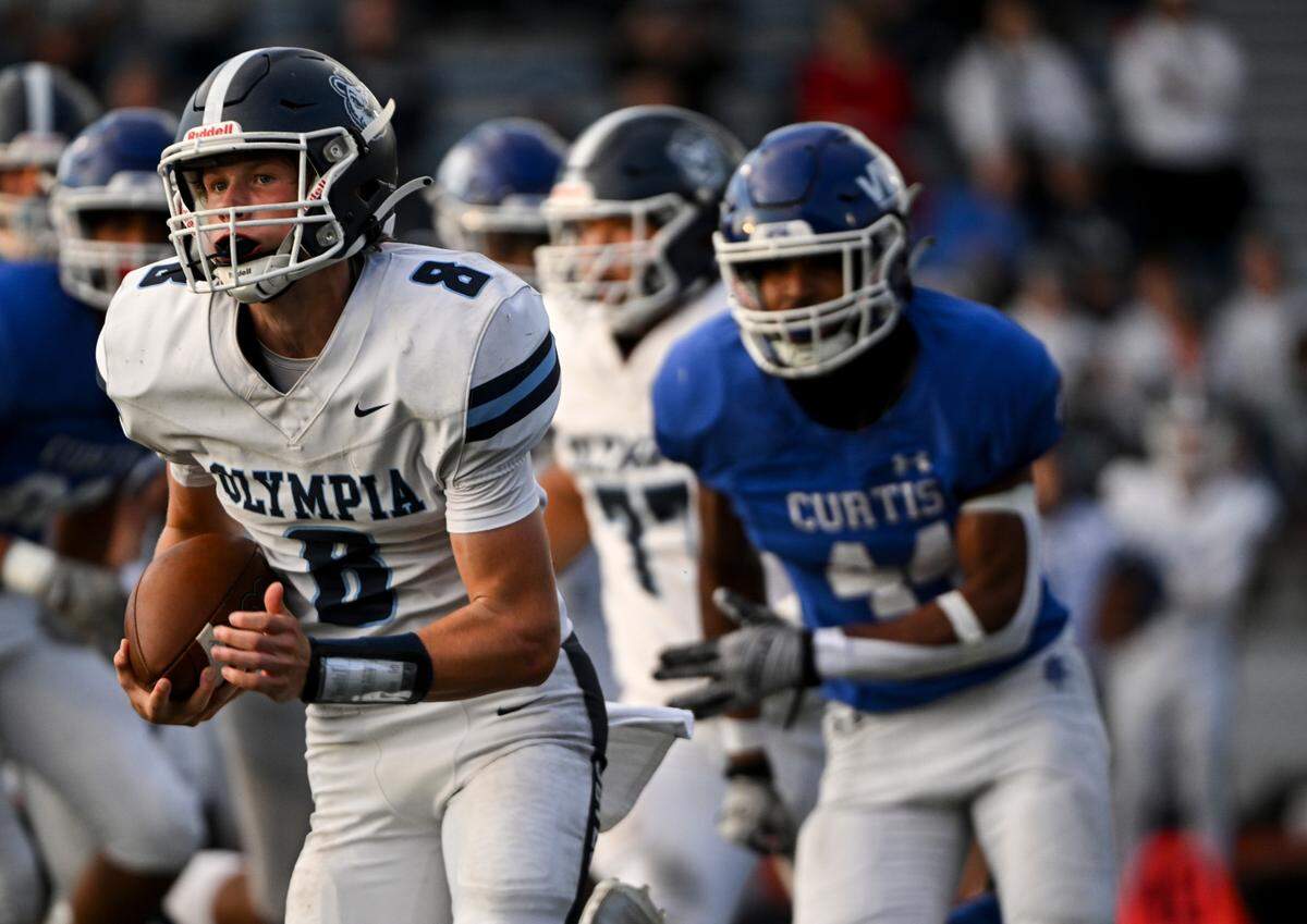 Olympia’s Drew Carlson (8) carries the ball during the first half of the high school football game abasing Curtis at Curtis Senior High School, Thursday, Aug. 31, 2023, University Place, Wash.