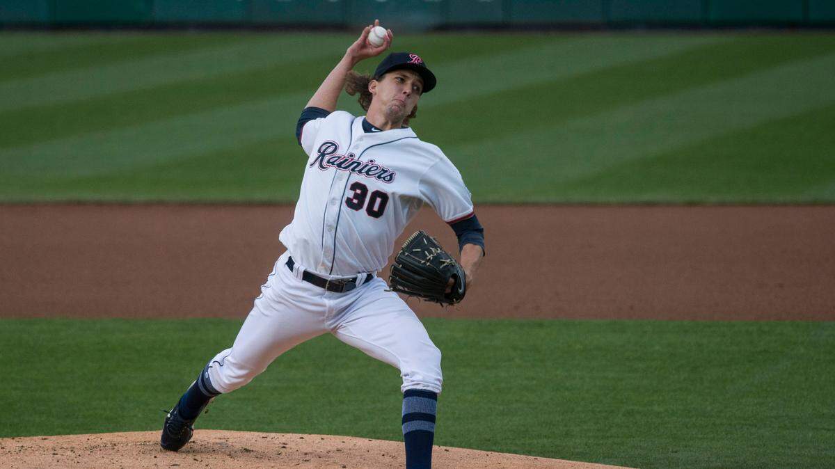 Tacoma Rainiers starter Logan Gilbert throws a pitch with The News Tribune sign in the background during his Triple-A debut against the El Paso Chihuahuas on Friday, May 7, 2021 at Cheney Stadium in Tacoma, Wash.