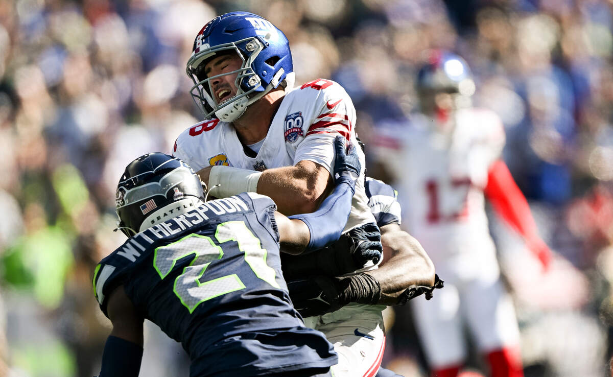 New York Giants quarterback Daniel Jones (8) is hit by Seattle Seahawks linebacker Derick Hall (58) and cornerback Devon Witherspoon (21) during the second quarter of the game at Lumen Field, on Sunday, Oct. 6, 2024 in Seattle, Wash.